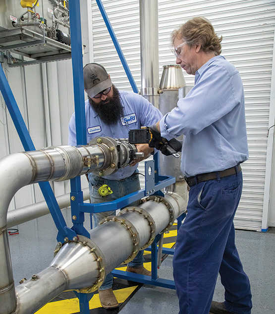 Two men wearing safety glasses working on ecto-lab pipes.