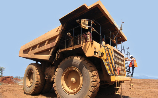 Giant mine hauling truck that has a person climbing up to the controls.