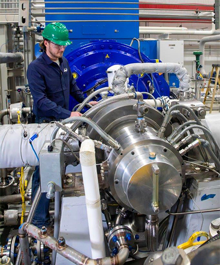 man wearing blue jumpsuit and hard hat working on Supercritical Transformational Electric Power (STEP) Demo pilot plant turbine