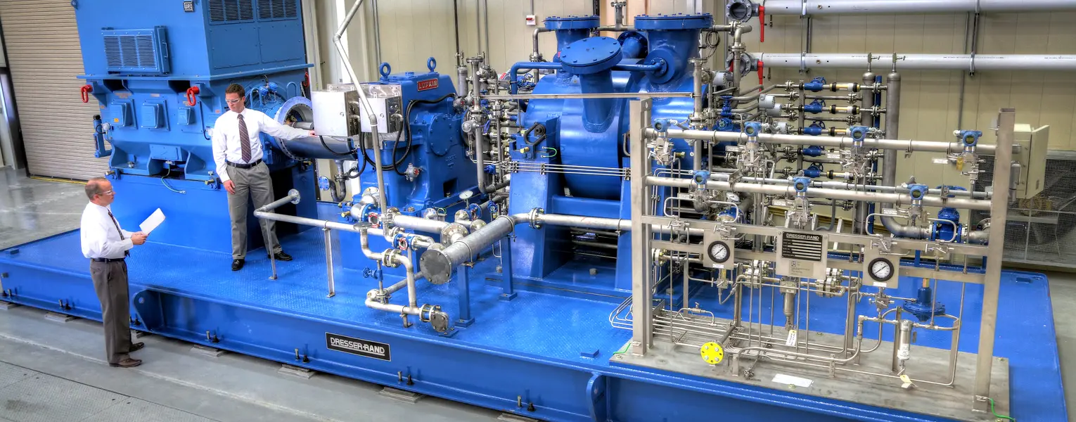 Two men standing near a gas turbine compressor