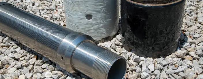 three pipes with varying degrees of erosion sitting on gravel