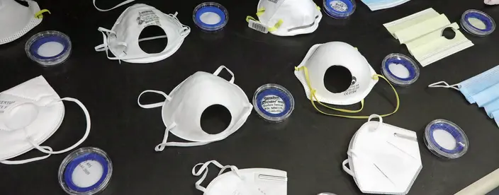 Several different colors and types of masks laid out on a table for testing