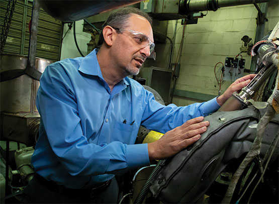 Worker leaning over a Low NOx Engine while working on it.