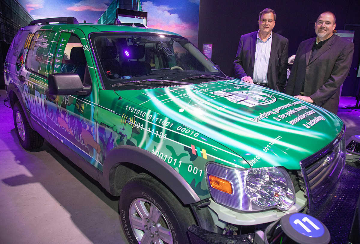 Steve Dellenback and Ryan Lamm stand near an automated vehicle known as MARTI, or Mobile Autonomous Robotics Technology Initiative.