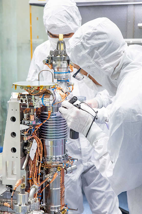 Two engineers dressed in white, using the MAss Spectrometer for Planetary EXploration (MASPEX) instrument 