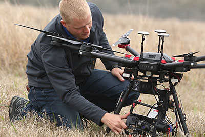 Technician inspecting a drone in a field