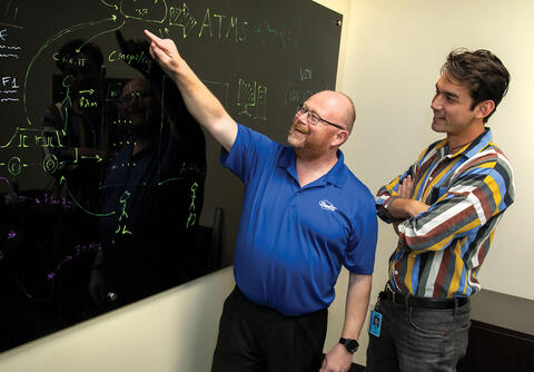 Michael Brown explaining cloud-fog-edge data to Jason Raiti in front of a blackboard