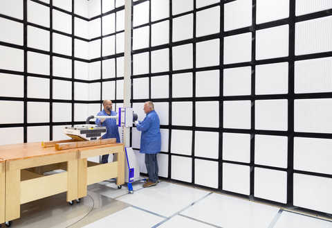 two men in blue lab coats working in SwRI's new semi-anechoic shield enclosure 