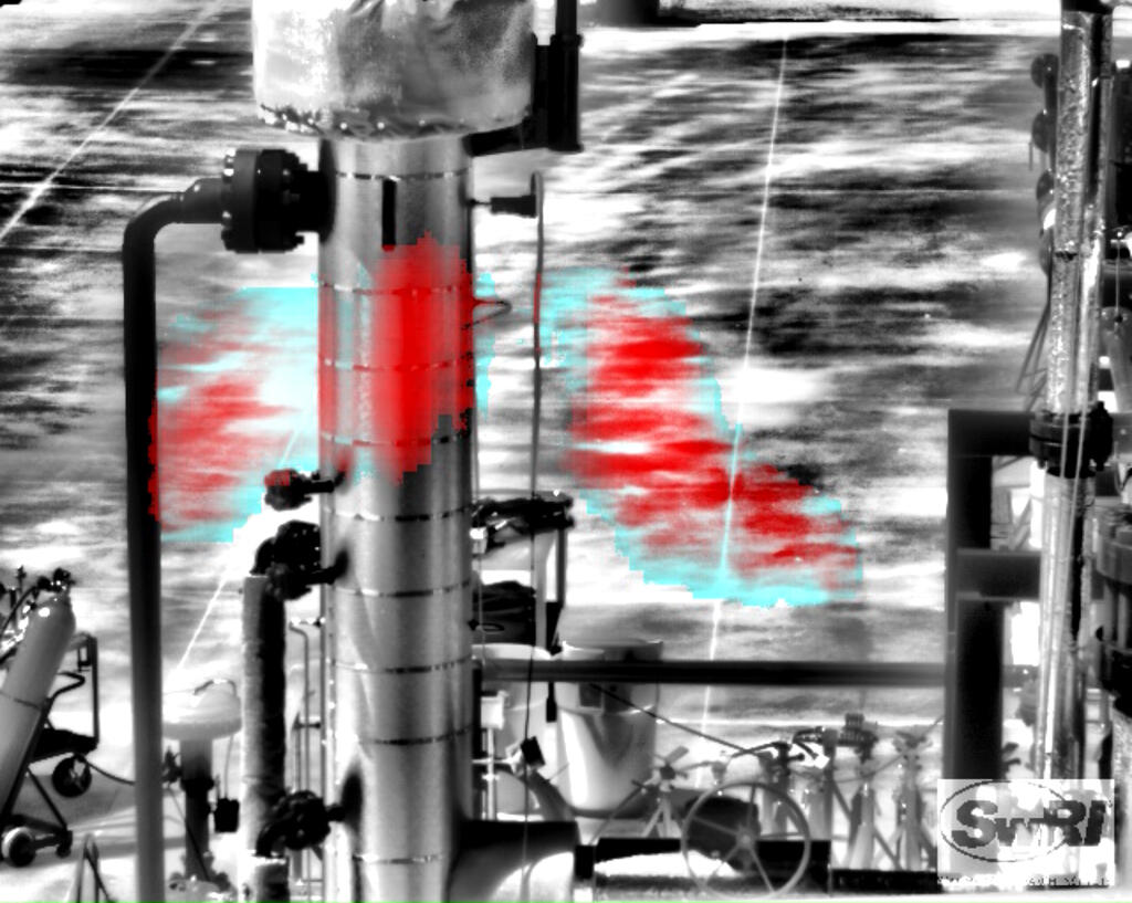 Black and white industrial piping with a blue and red plume of methane in the middle 